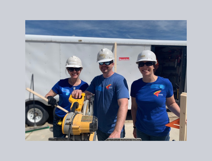 Three volunteers outside next to saw